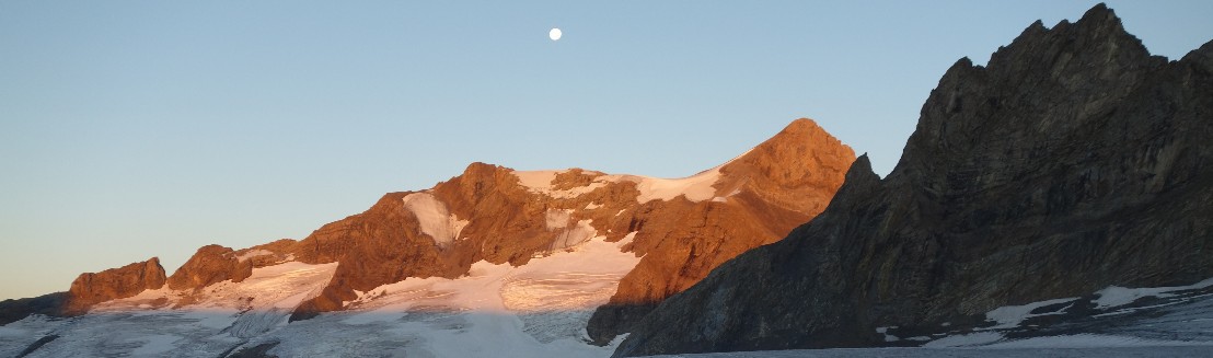 Das Schaerhorn im goldenen Morgenlicht. Darueber im blauen Himmel ist der Mond nocht sichtbar.