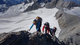 Drei Personen klettern auf einem Felsgrat auf den Clariden
