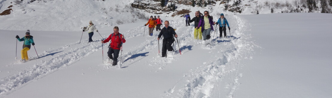 Eine Schneeschuhgruppe in bunter Kleidung auf einer Schneeschuhwanderung.
