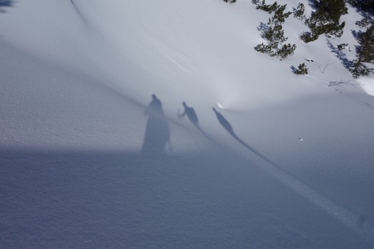 Der Schattenwurf von drei Menschen auf Pulverschnee.