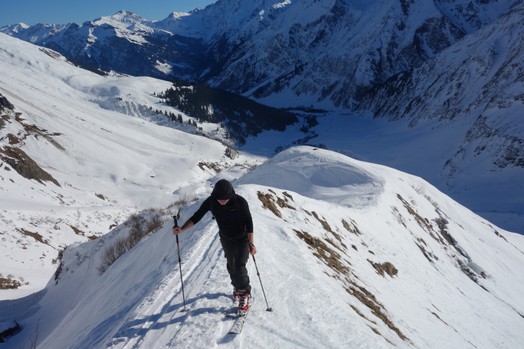 Ein Skitourengaenger in schwarzer Kleidung im Aufstieg auf der Spitzegg.