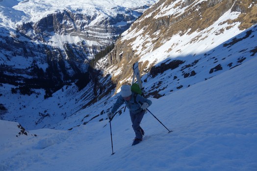 Eine Frau traegt die Skis auf dem Rucksack.